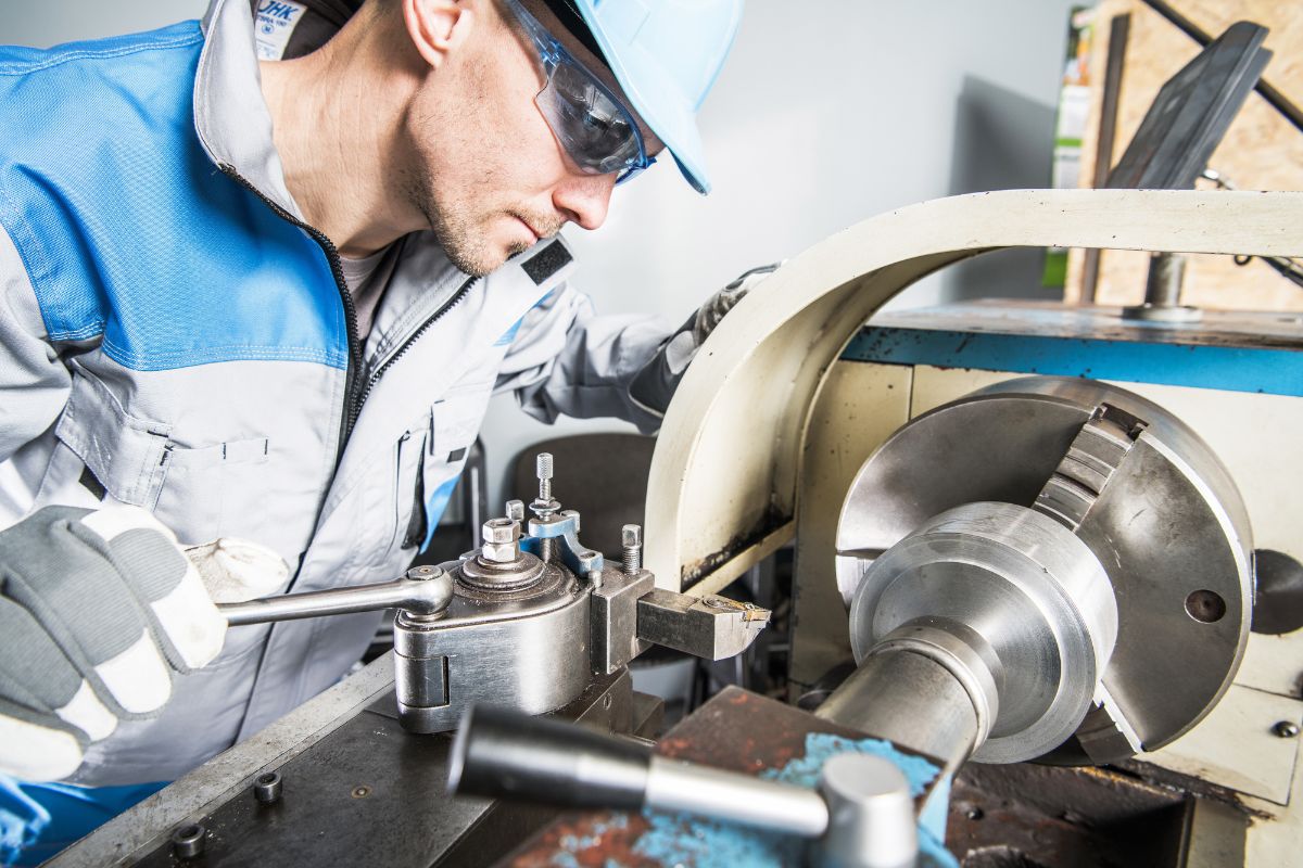 Industritekniker arbejder med praecisionsdrejning paa drejebaenk i metalproduktion