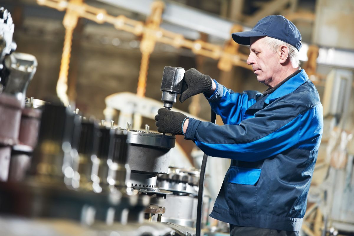 Industritekniker udfoerer vedligehold og praecisionsmontage paa industriel produktionsmaskin